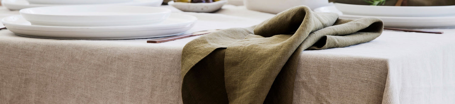 Linen Table Napkin in Olive styled on a Linen Tablecloth in Natural.