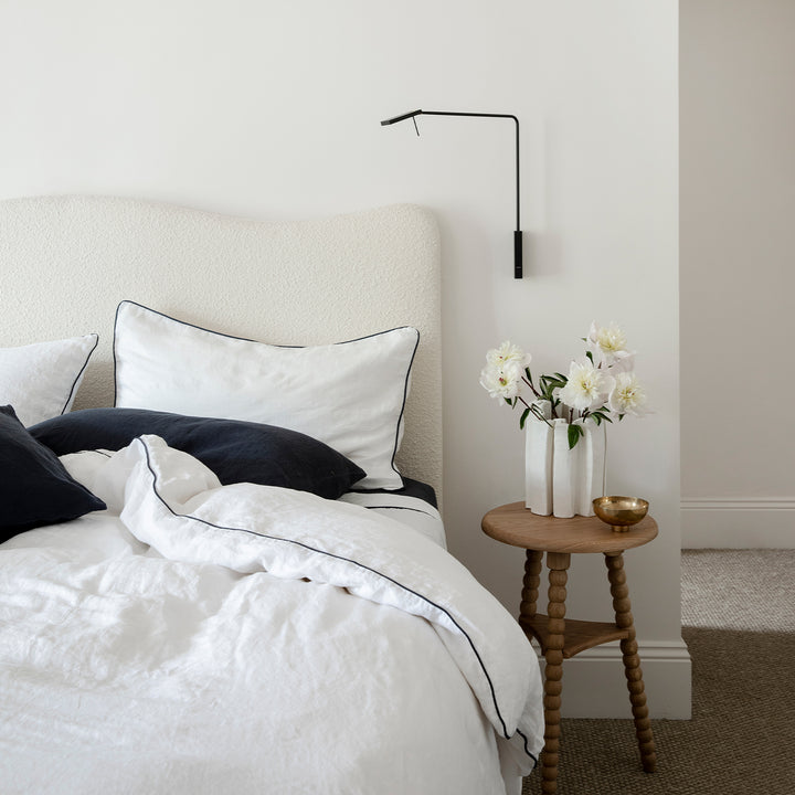 A cream bed dressed in White and Navy Piped bed Linen, styled with a Navy Fitted Sheet and Pillowcases