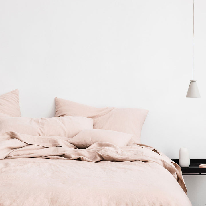 Bed styled with Blush duvet cover set and Blush sheet set. A lamp hangs from the ceiling, and on the black bedside table is a white ceramic vase. Sizes: Twin, Queen, King, California King