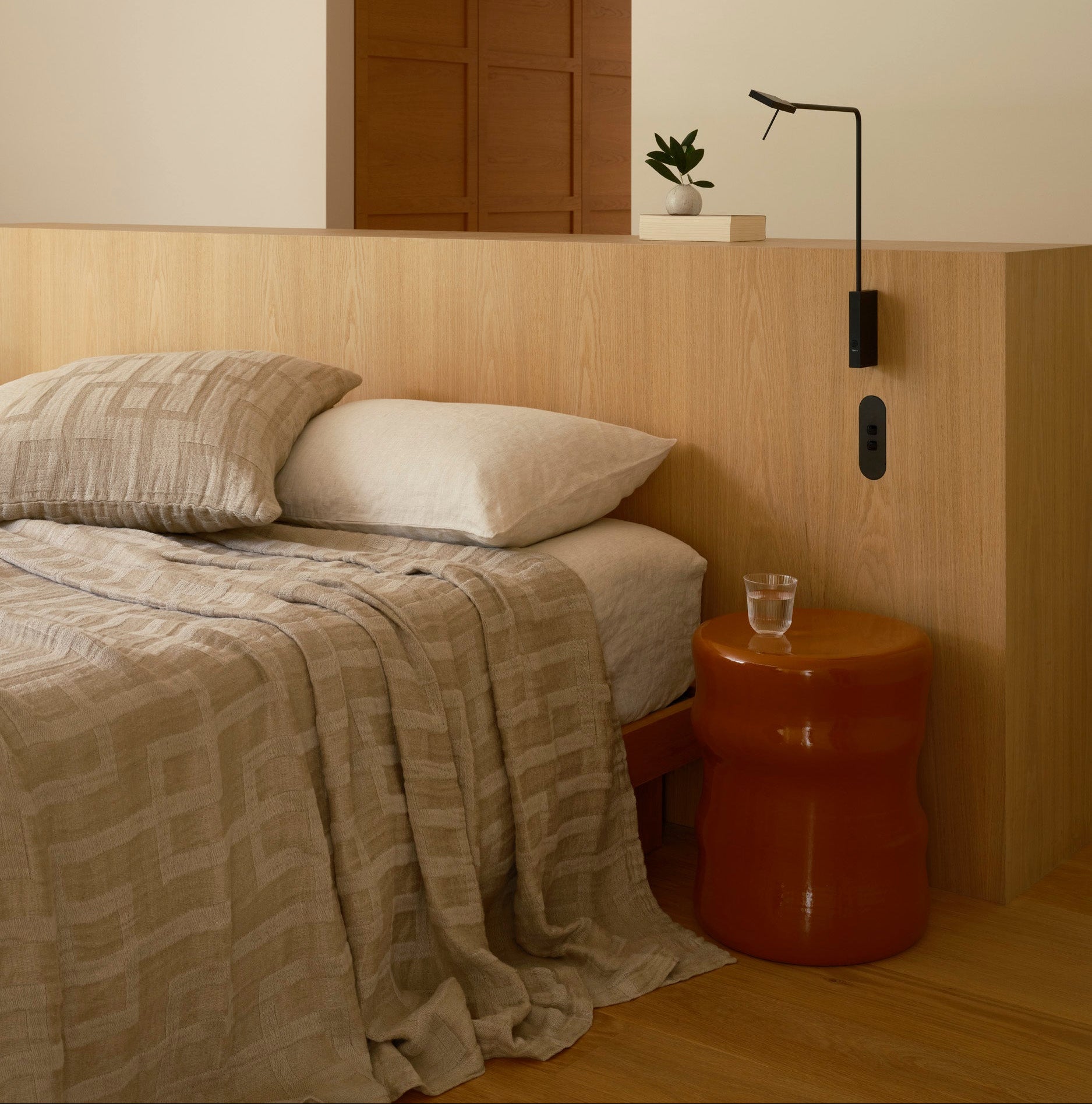 Close-up of a textured brown blanket and pillows on a bed.