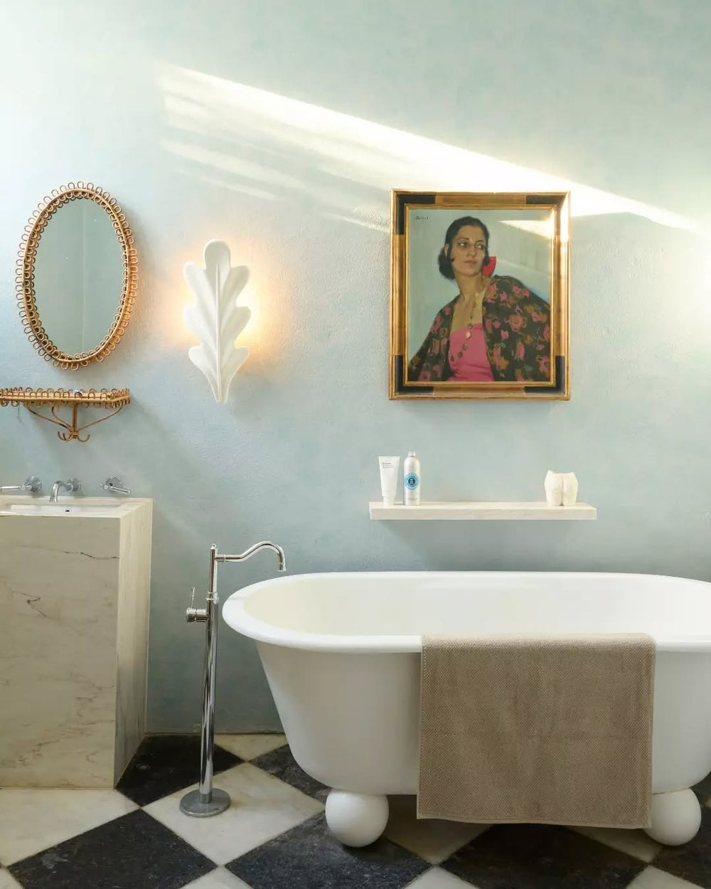 Bathroom interior with a freestanding bathtub, checkered floor, and wall art.