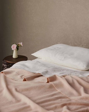 Soft blush NZ Merino Wool throw from CULTIVER, showing its cozy texture and elegant drape on a neutral background.