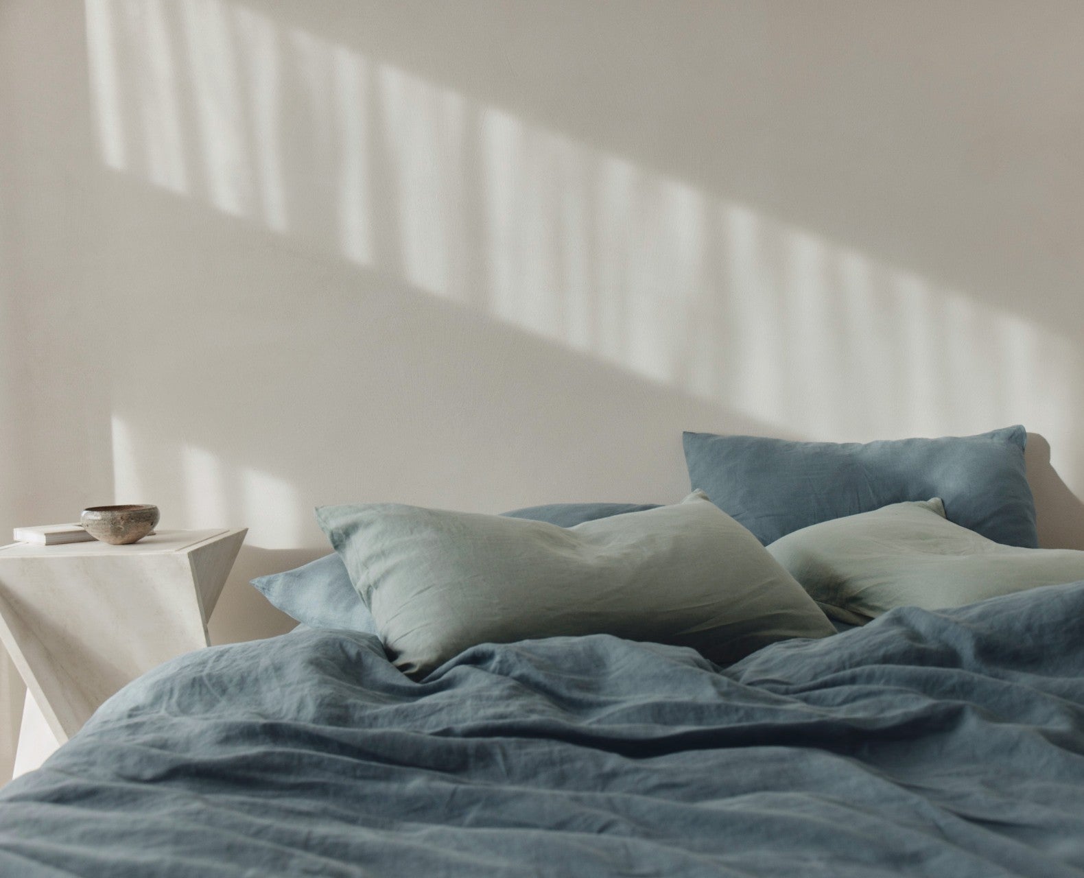 Close-up of a textured brown blanket and pillows on a bed.