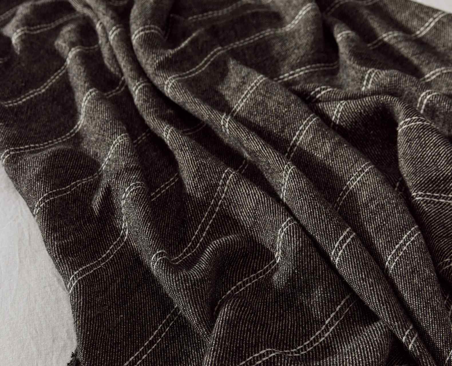 Close-up of a textured brown blanket and pillows on a bed.