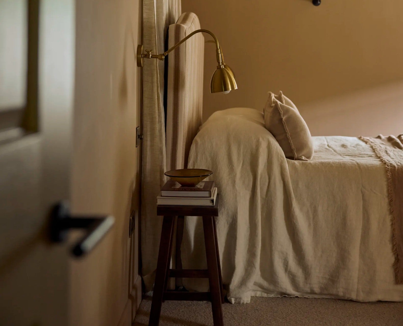 Bedroom with green bedding and wooden headboard, dimly lit.