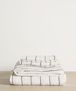 Stack of folded striped blankets on a wooden surface with a light background