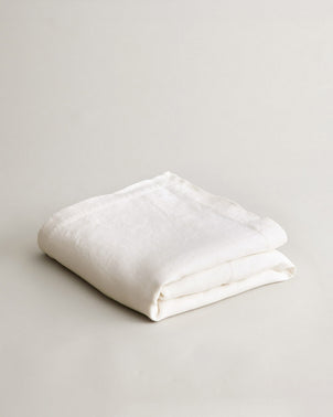 Ivory heavyweight linen bedcover by CULTIVER, folded to showcase soft, textured fabric and elegant natural design.