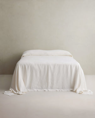 Creamy ivory heavyweight linen bedcover by CULTIVER draped smoothly over a bed, showcasing its soft, textured fabric and elegant design.