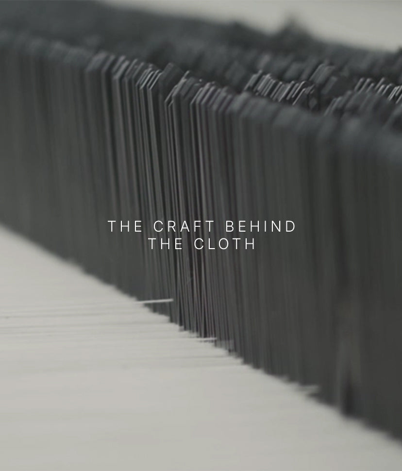 Close-up of vertical threads on a loom, blurred in the background, with the words THE CRAFT BEHIND THE CLOTH centered in white text.