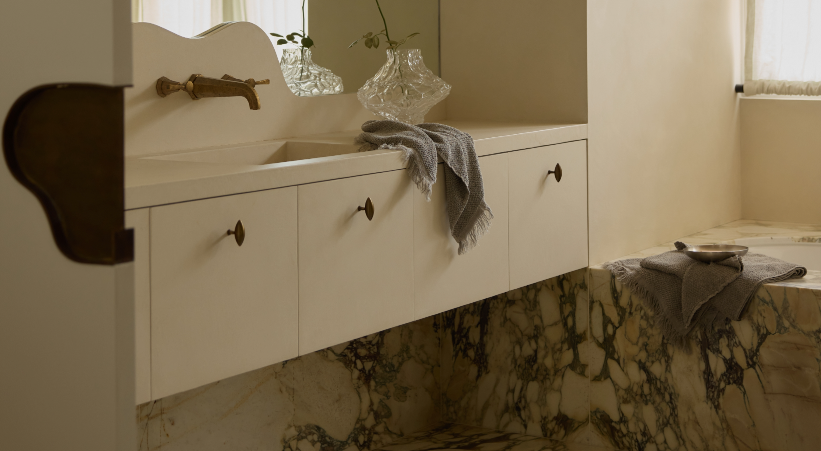 Bathroom vanity with white cabinets, marble countertop, and decorative elements.