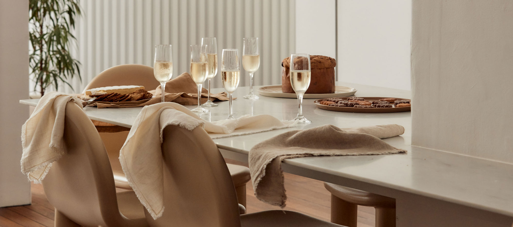 Dining table set with wine glasses, bread, and plates in a modern kitchen.