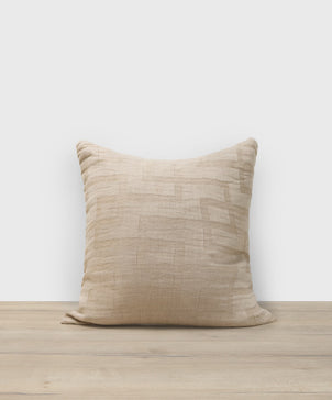 Beige pillow on a wooden surface with a white background