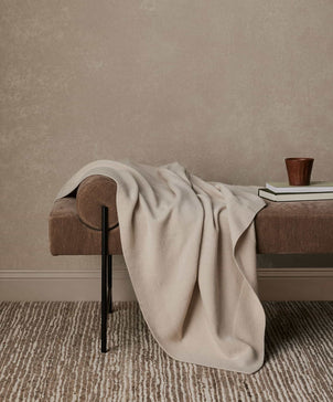 Soft 100% NZ Merino Wool throw in oatmeal color from CULTIVER, displayed draped on a cozy sofa for stylish comfort.