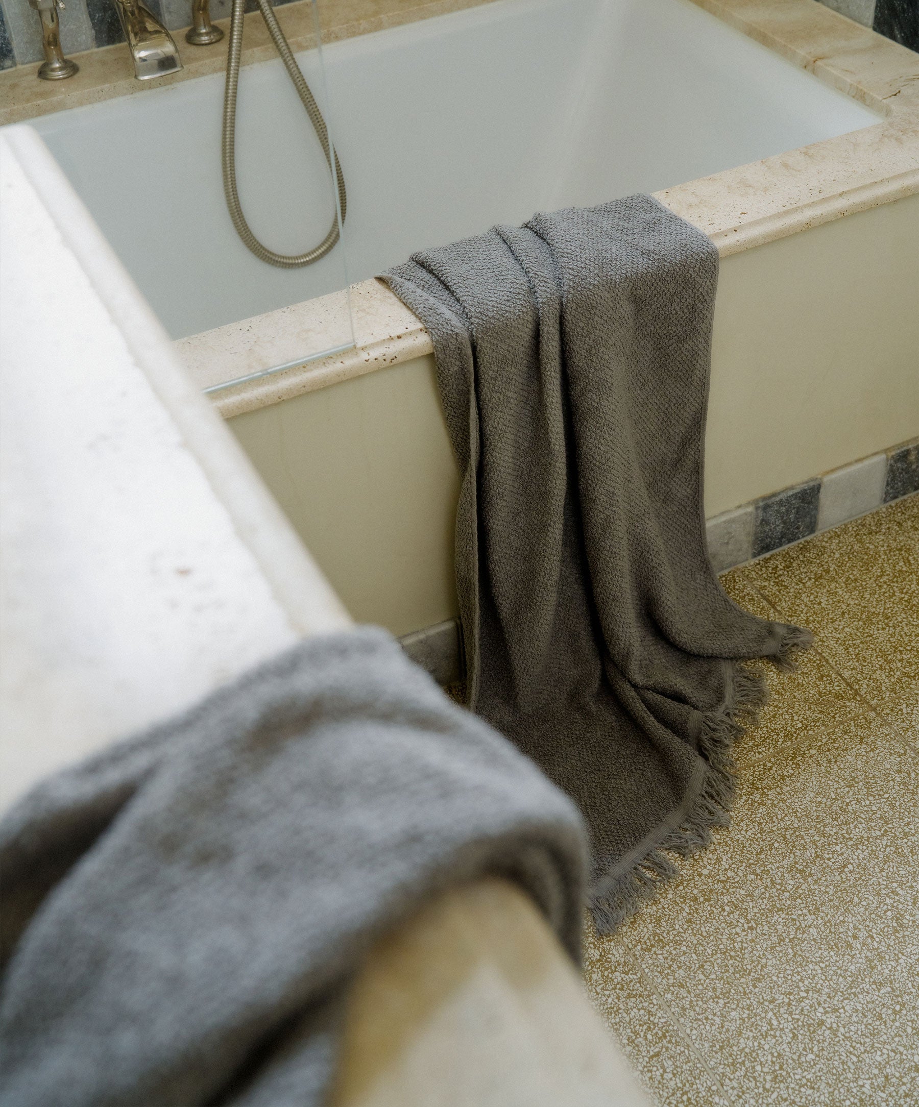 Gray towel draped over a bathtub in a bathroom setting