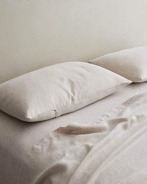 Set of two natural linen pillowcases from CULTIVER styled on a bed, showcasing soft, breathable bed linen in a neutral color.