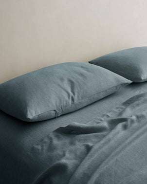 Set of 2 blue linen pillowcases by CULTIVER styled on a bed, showcasing soft, textured bed linen for a cozy bedroom look.