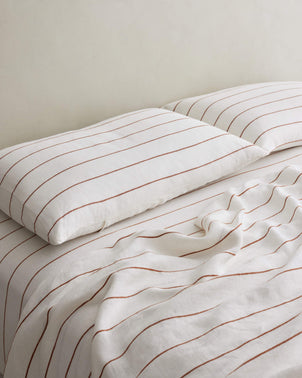 Set of 2 CULTIVER linen pillowcases with cedar stripe pattern styled on a bed for a cozy, modern bedroom look.