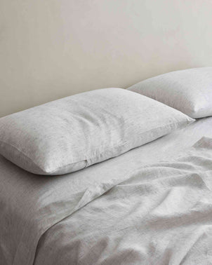 Set of 2 CULTIVER linen pillowcases with pinstripe design, styled on a bed with cedar-colored bedding for a modern, cozy look.