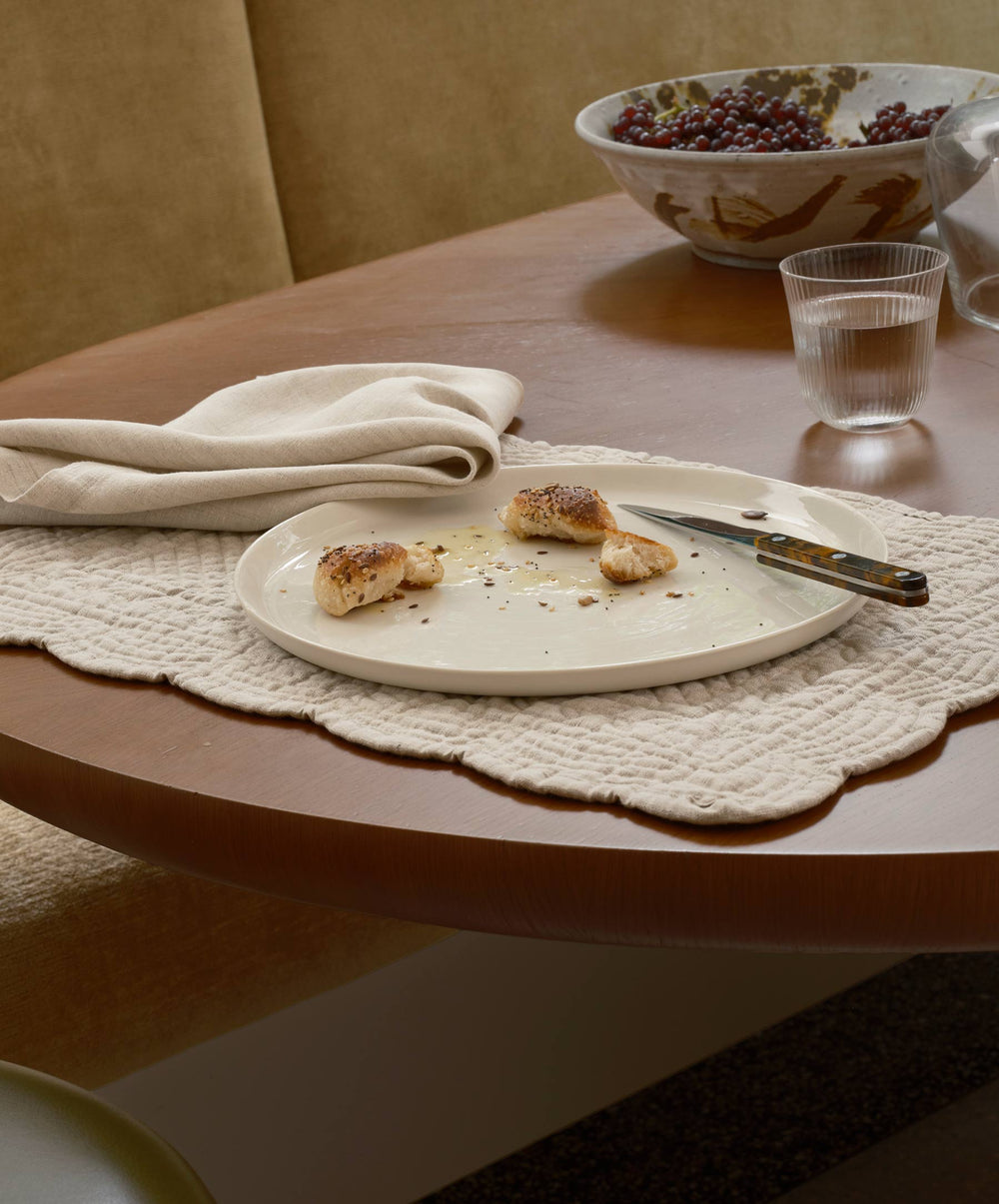 Natural-colored scalloped linen placemats by CULTIVER, showing elegant, textured fabric with scalloped edges on a table setting.