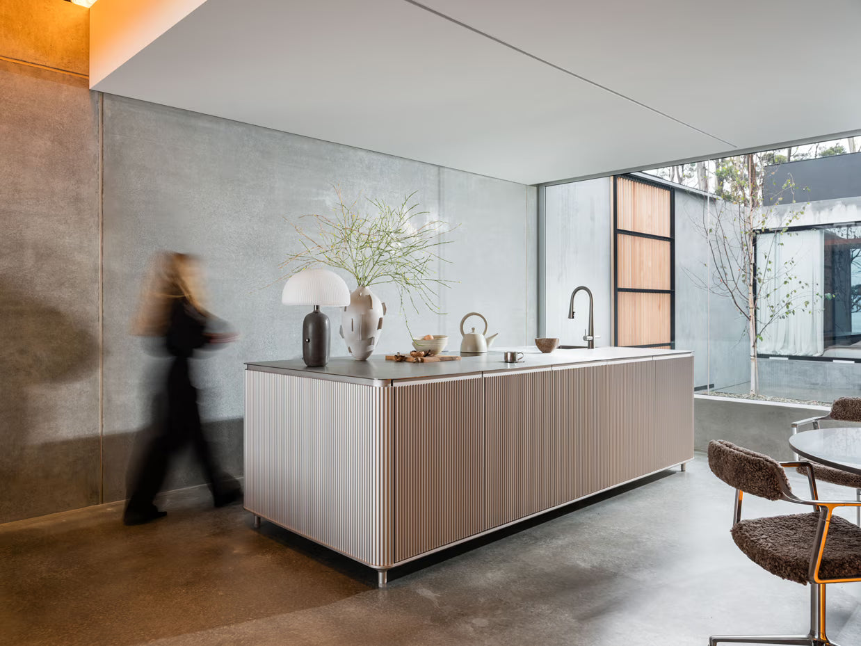 Modern kitchen with a large island and a person walking in the background