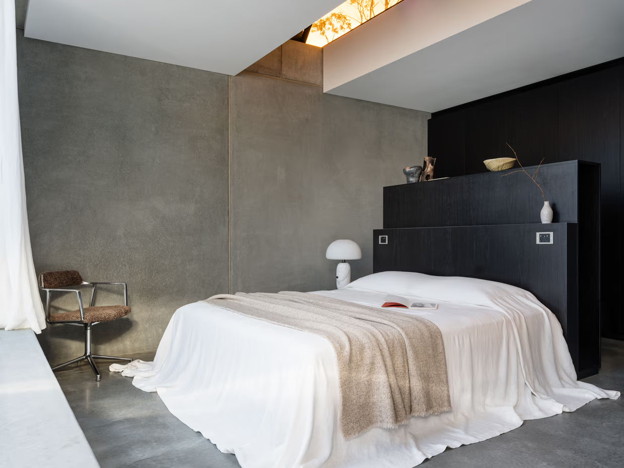 Modern bedroom with a bed, chair, and abstract wall art.