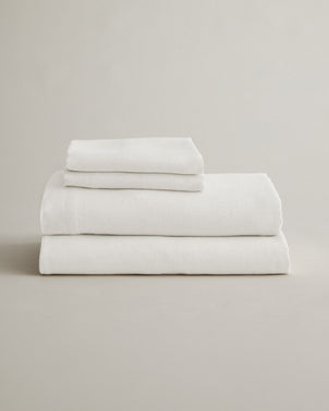 Creamy ivory linen sheet set with matching pillowcases from CULTIVER, neatly folded, showcasing soft, breathable bed linen.