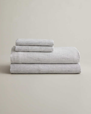 CULTIVER linen sheet set with pillowcases in pinstripe pattern, folded neatly, showcasing soft, breathable bed linen fabric.