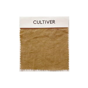 A square linen swatch in warm brown, labeled Complimentary Swatch - Sand, is shown on a white background. The fabric has a naturally textured look with pinked edges—ideal for choosing premium home textiles.
