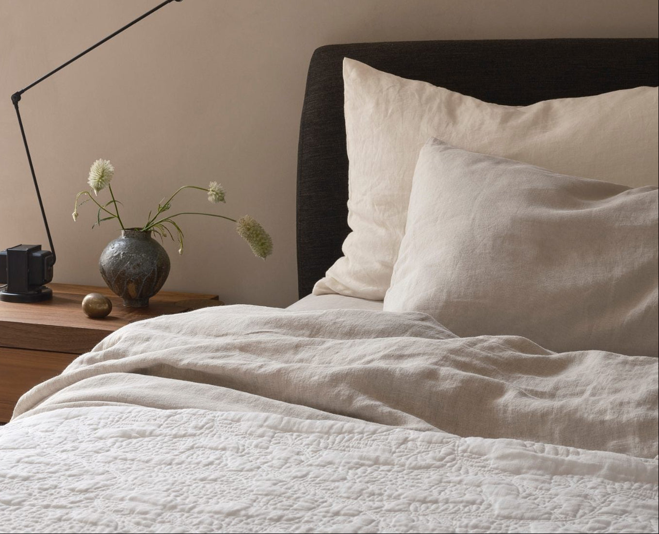 Bedroom with green bedding and wooden headboard, dimly lit.