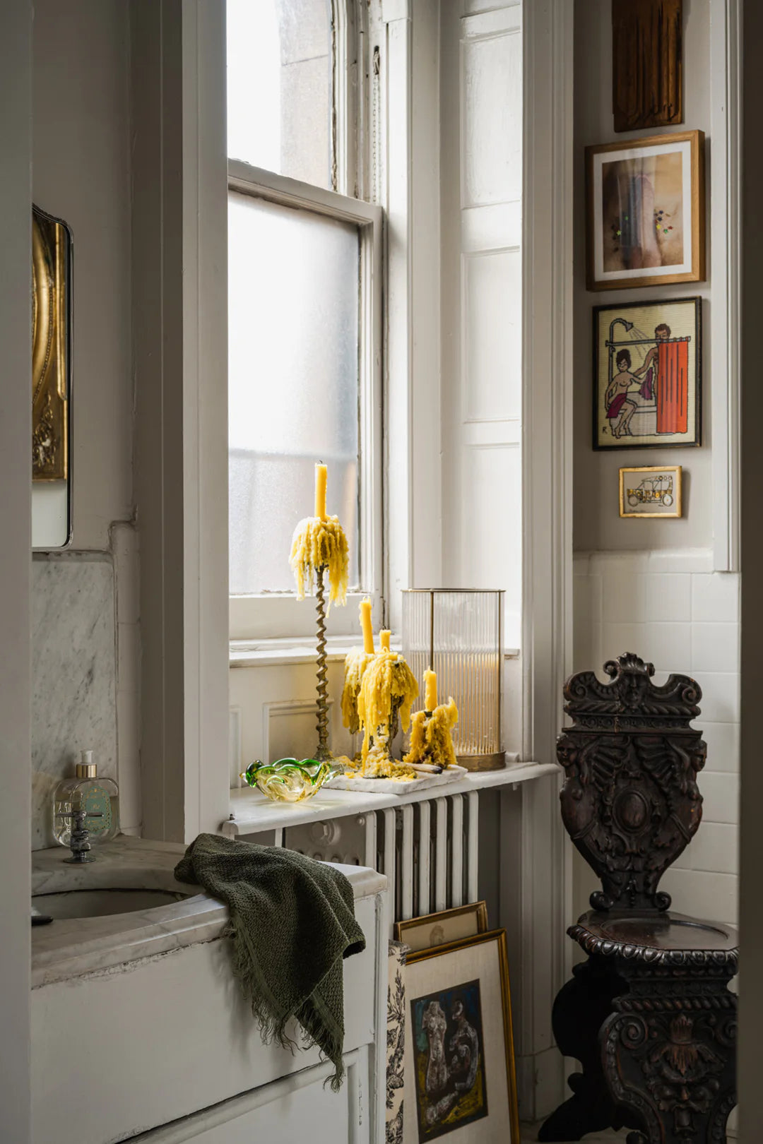 Decorative radiator with yellow candles and framed pictures in a room.