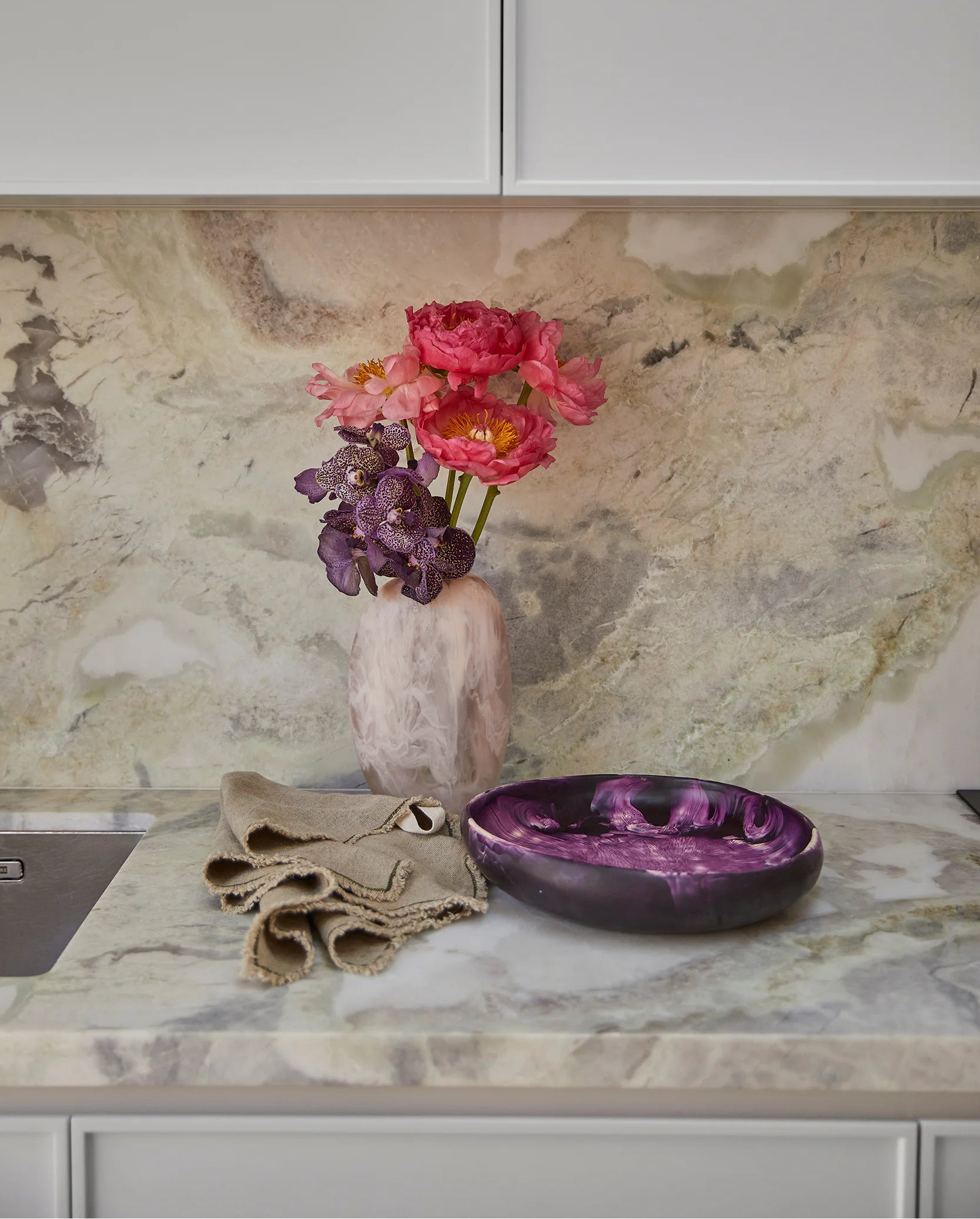Decorative items on a kitchen counter with a marble backsplash