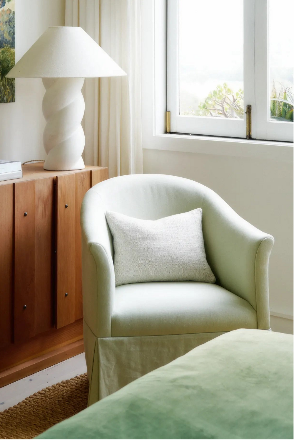 Neatly made bed with white bedding in a room with wooden walls and a vase of white tulips.