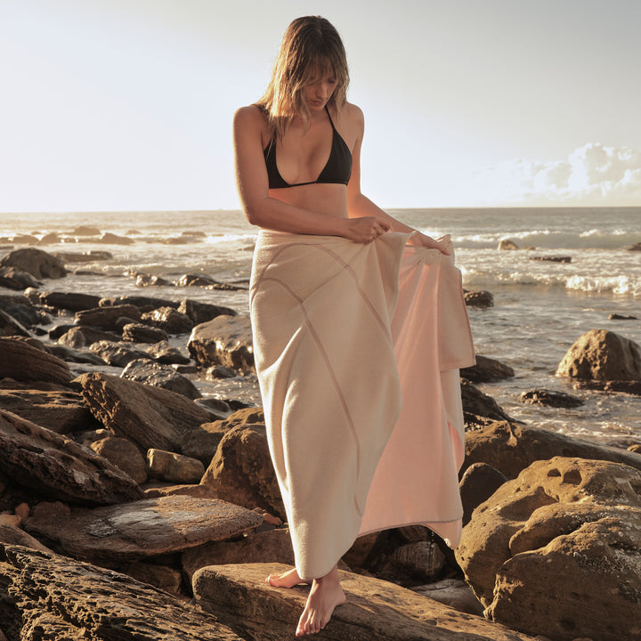 A woman wrapping a Beach Towel in Rose around her waist