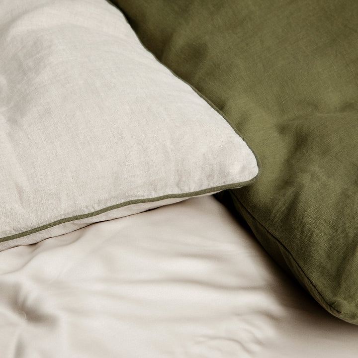 A close up of a Natural and Forest Piped Pillowcase paired with a Forest Pillowcase