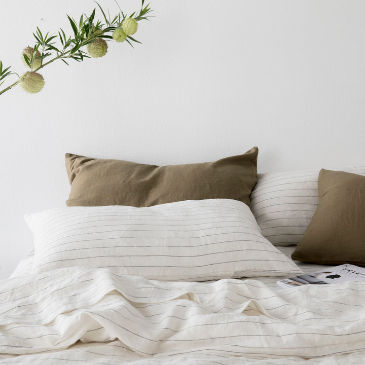 A bed dressed in Pencil Stripe bedlinen, with contrasting Pillowcases in Olive