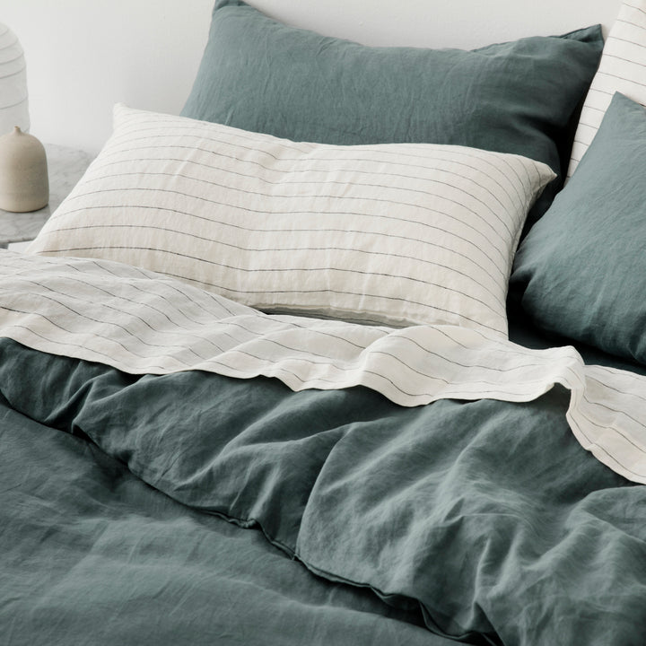 A combination of a Set of 2 Linen Pillowcases and a Flat Sheet in Pencil Stripe, and a Duvet Cover Set in Bluestone on a bed.