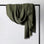 An Estela Linen Waffle Throw in Forest hanging on a rail