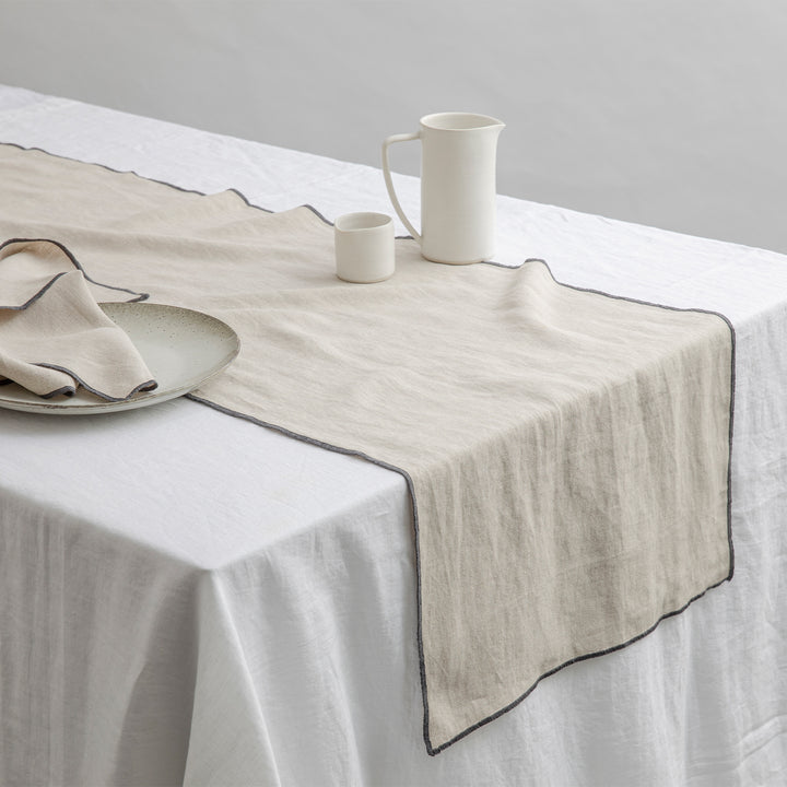 Cara Edged Table Runner in Slate on a Linen Tablecloth in White