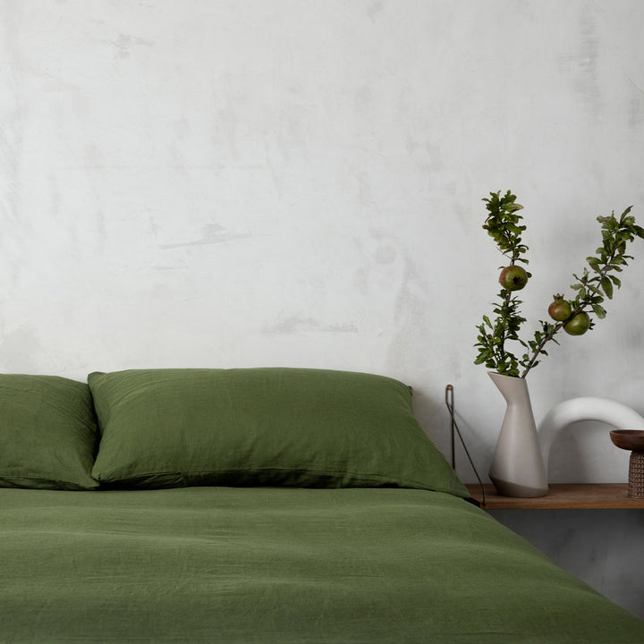 A bed dressed in Forest bed linen, styled with a vase and greenery. Sizes: Queen, King