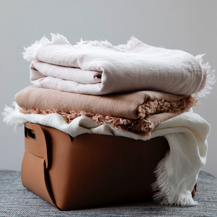 A stack of Freya Linen Throws in Blush, Fawn and Snow