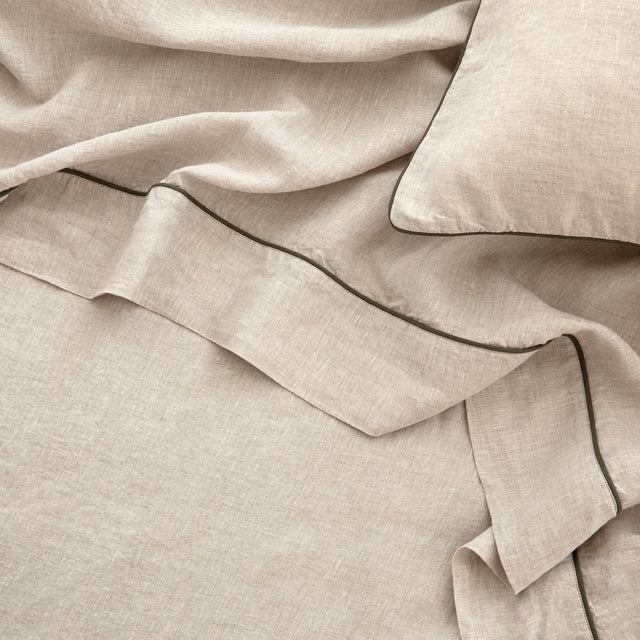A close up of the Piped Linen Flat Sheet in Natural and Forest