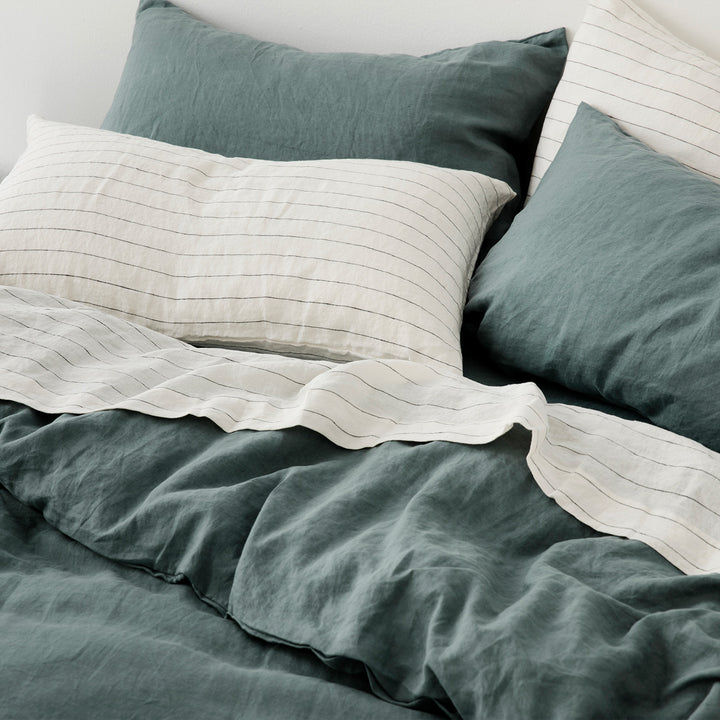 A bed styled with a Linen Duvet Cover Set in Bluestone and Linen Sheet Set with Pillowcases in Pencil Stripe.