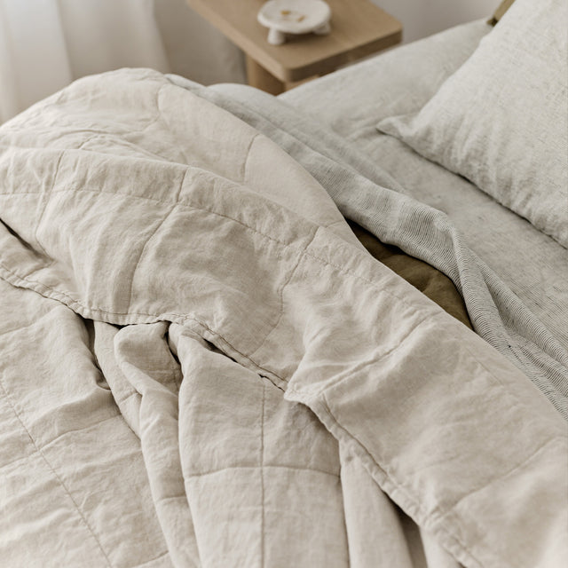 A Quilted Bedcover in Natural paired with Pinstripe and Olive bed linen