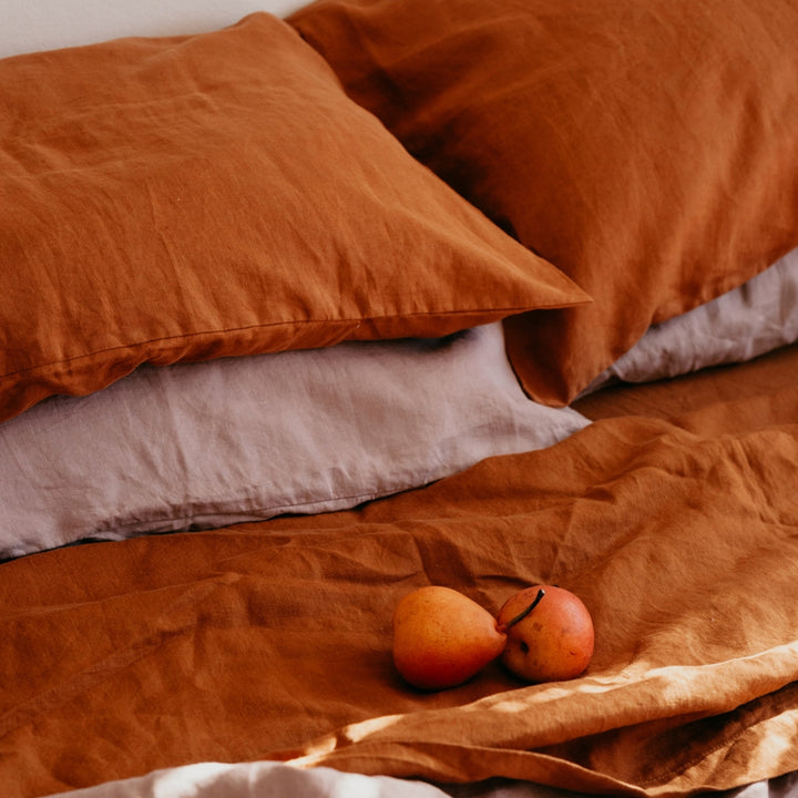 A close up of a bed dressed in Cedar and Dusk bed linen, styled with fruit. Sizes: Queen, King