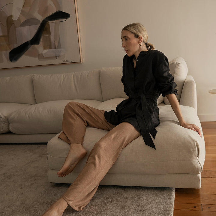  A woman sitting on a sofa in a lounge room wearing a Cristi Linen Shirt in Black