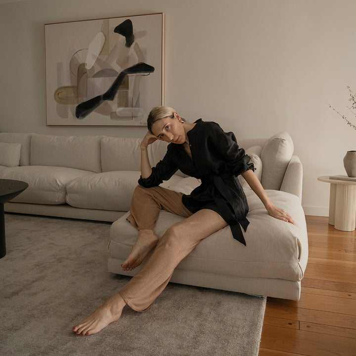  A woman sitting on a sofa in a lounge room wearing a Cristi Linen Shirt in Black