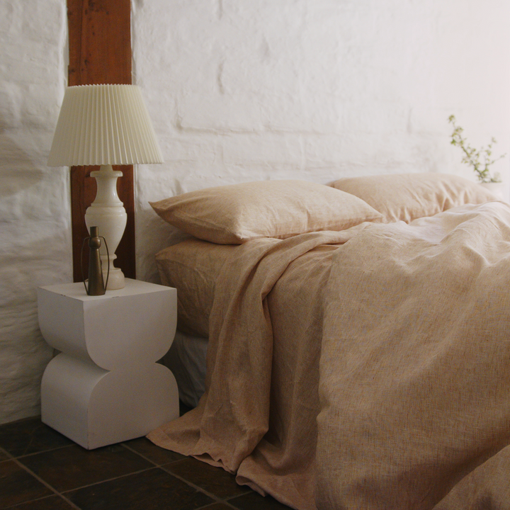 A bed dressed in Cinnamon bed linen, styled with a modern bedside table 