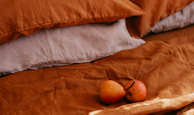 Close up shot of Cultiver pillows and flat sheet in Cedar and Dusk colors.