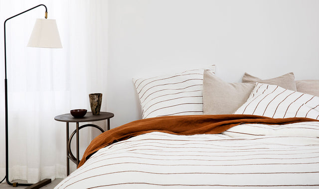 Bed styled with Cultiver linen bedding including a Cedar Flat Sheet, Natural Pillowcases, and a Cedar Stripe Duvet Set.