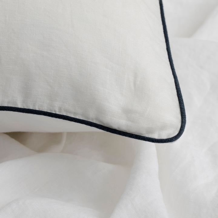 A close up of a Piped Linen Pillowcase in White and Navy